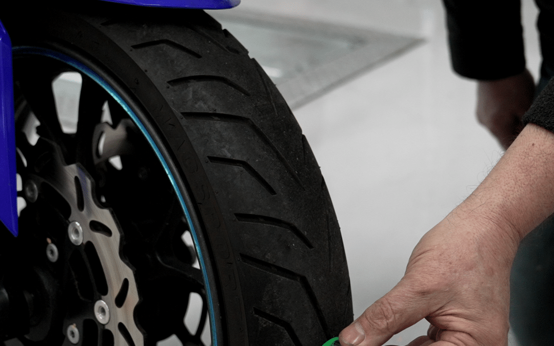 Someone checking tread depth of motorbike tyre